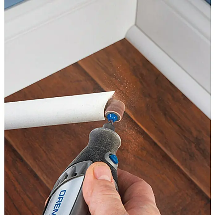 Dremel EZ SpeedClic Schleifdorn SC 407 - 13 mm, 3 -tlg. - Ein Dremel-Rotationswerkzeug wird zum Schleifen von Fußleisten verwendet, wobei feine Staubpartikel entstehen. Perfekt für detailgenaue Holzarbeiten.