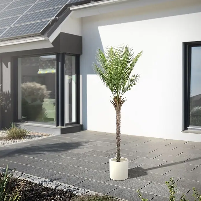 Künstliche Palme 180 cm groß im Topf für Indoor/Outdoor -  - Hohe Topfpalme mit grünen Blättern und braunem Stamm in einem weißen Zylindergefäß, als Außendeko auf einer modernen Terrasse.