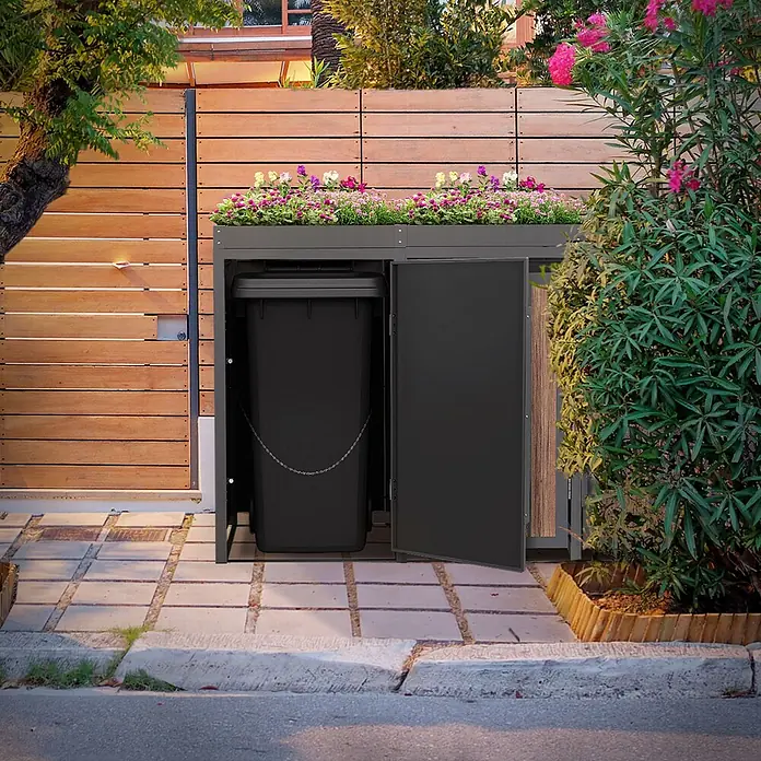 ML-Design Mülltonnenbox 4er 240L Pflanzdach 260x80x124 Anthrazit-Holzoptik -  - Dunkelgraue Mülltonnenbox für den Außenbereich mit bepflanzter Oberseite, geöffnete Tür zeigt schwarzen Behälter, neben Holzzaun.