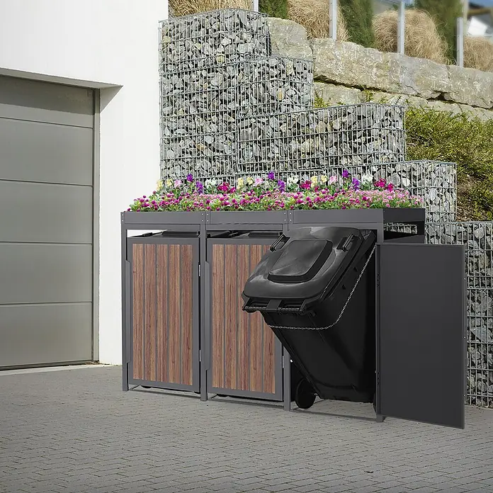 ML-Design 3x Mülltonnenbox 240L Pflanzdach 196x80x124cm Anthrazit-Holzoptik -  - Mülltonnenbox aus Metall/Holzoptik mit bepflanztem Dach neben Garage. Eine schwarze Tonne ist herausgezogen.