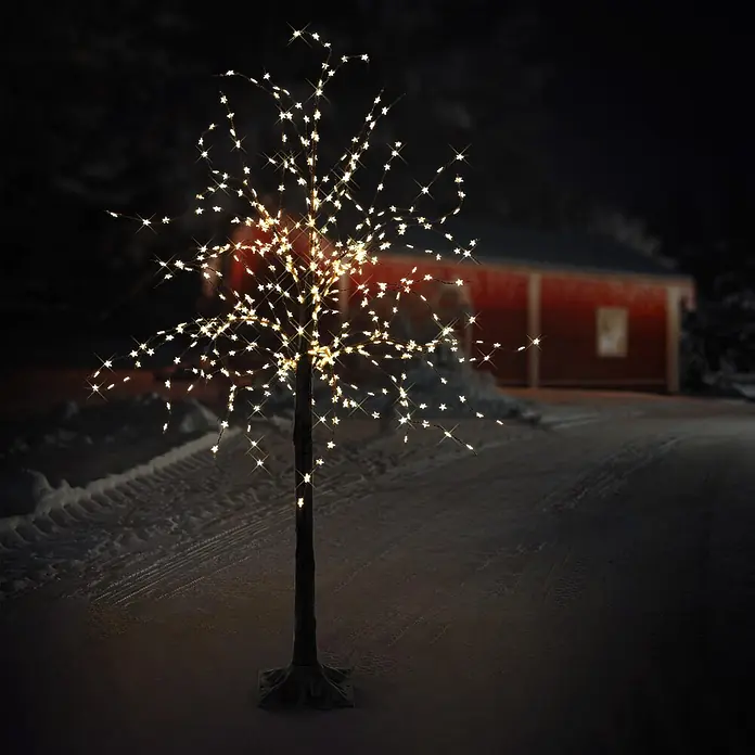 LED-Baum 120 cm mit 480 warmweißen LEDs Außen IP44 -  - Ein beleuchteter LED-Baum mit warmweißen Sternenlichtern steht im Freien in einer verschneiten Nacht und leuchtet hell.