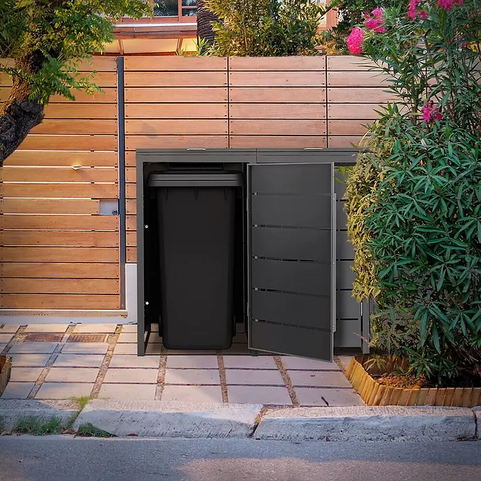 Mülltonnenbox 3er 240L 196x80x120 cm Anthrazit aus Stahl wetterfest -  - Dunkelgraue Mülltonnenbox für den Außenbereich mit geöffneter Tür, die eine schwarze Tonne zeigt, neben einem Holzzaun.