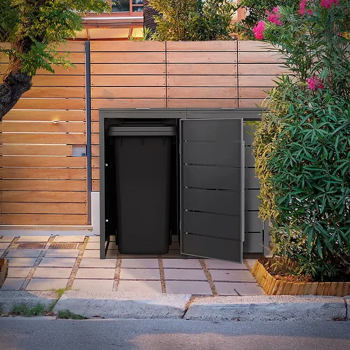 Mülltonnenbox 2er 240L 132x80x120 cm Anthrazit aus Stahl wetterfest -  - Dunkelgraue Outdoor-Aufbewahrungsbox mit offener Tür, die eine schwarze Mülltonne enthält. Sie steht im Garten an einem Holzzaun.
