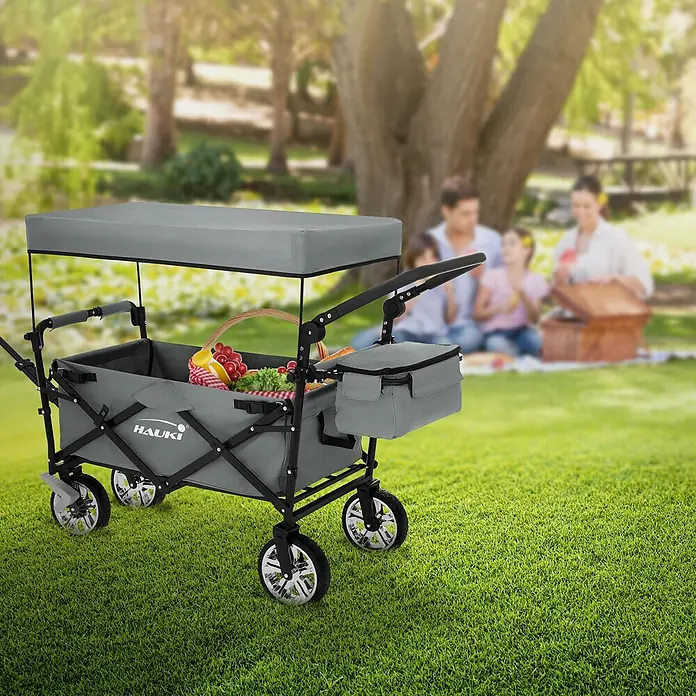 Bollerwagen faltbar mit Dach Grau XXL für Kinder Strand Picknick -  - Grauer faltbarer Bollerwagen mit Dach, gefüllt mit Picknickartikeln, auf Gras vor einer Familie beim Picknick.
