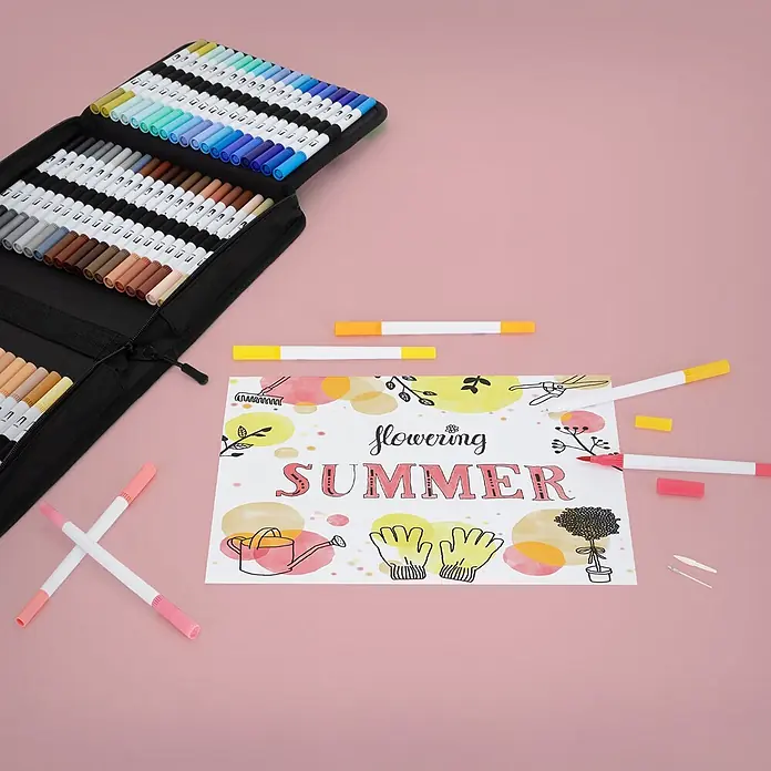 Dual Brush Pen Set 120 Farben Wasserbasis -  - Ein großes schwarzes Etui mit farbenfrohen Dual-Tip-Markern, präsentiert mit einer 'Flowering Summer'-Zeichnung und einzelnen Stiften auf rosa Untergrund.