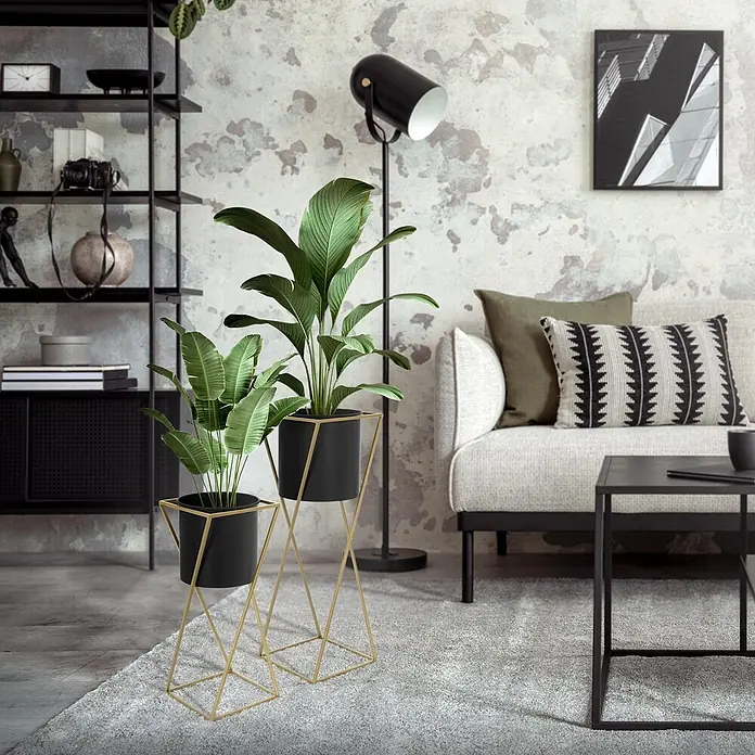 Blumenständer 2er Set Schwarz-Gold 21x21x51 cm/24x24x70,5 cm aus Stahl -  - Zwei Pflanzenständer mit schwarzen Töpfen und goldenen geometrischen Gestellen, die grüne Pflanzen in einem modernen Wohnzimmer präsentieren.