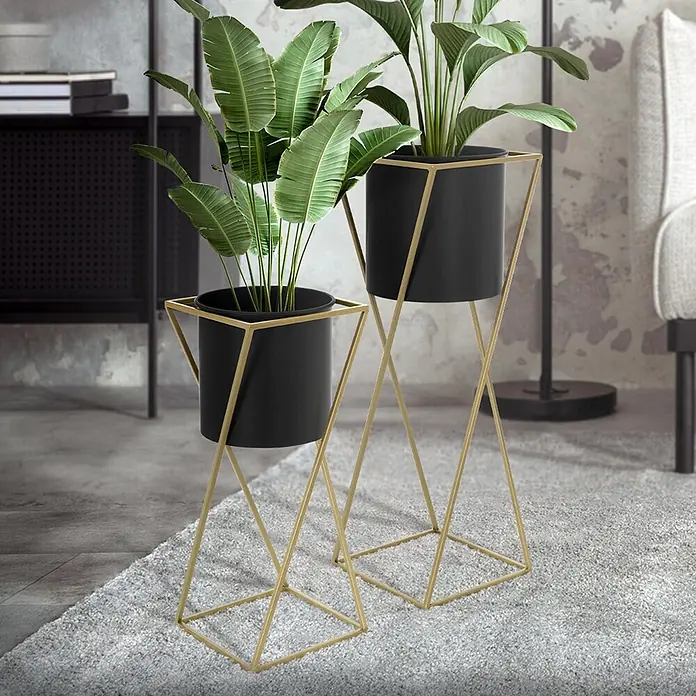 Blumenständer 2er Set Schwarz-Gold 21x21x51 cm/24x24x70,5 cm aus Stahl -  - Zwei Pflanzenständer mit schwarzen Töpfen und goldenen geometrischen Metallrahmen halten grüne Pflanzen in einem Wohnzimmer.