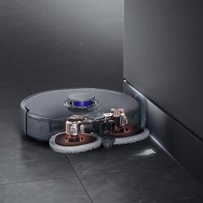 Narwal Saugwischroboter Freo Z ultra - Saugkraft: 12.000 Pa - Ein dunkelgrauer Saugroboter mit transparenter Hülle zeigt sein orange beleuchtetes Wischsystem, das eine dunkle Wand entlang reinigt. Ein Pfeil zeigt die Richtung.