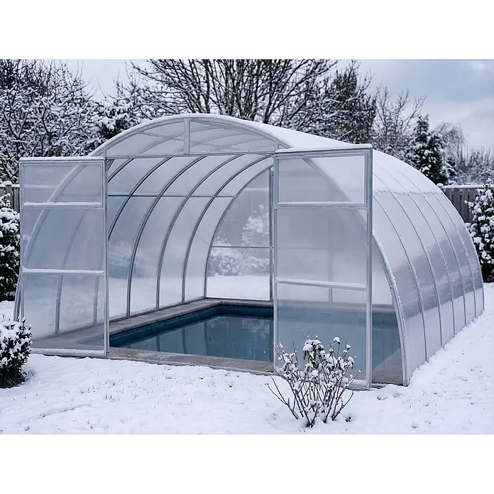 Garten Dream Poolüberdachung Sigma, 6mm Polycarbonat - L x B x H: 1.000 x 400 x 220 cm - Ein gewölbtes, durchsichtiges Pool-Dach mit silbernen Rahmen, teilweise mit Schnee bedeckt, schützt einen Pool. Die Vordertüren sind offen.