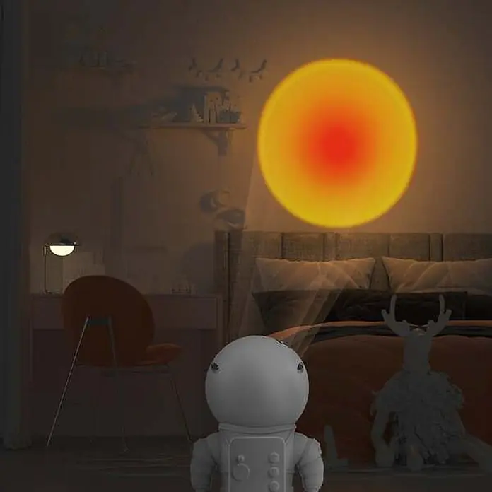 Mob Lámpara de sobremesa LED Astrolight Sun - 5 W, L x An x Al: 6,5 x 6 x 12 cm, Blanco, Blanco cálido, Sun - Proyector astronauta blanco proyectando una luz cálida de atardecer en la pared de un dormitorio.