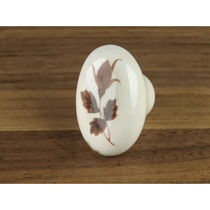 SOTECH Möbelknopf Inga - Durchmesser: 22 mm, Porzellan, cremeweiß - Keramik-Schubladengriff mit braunem Blumenmuster auf Holzoberfläche.