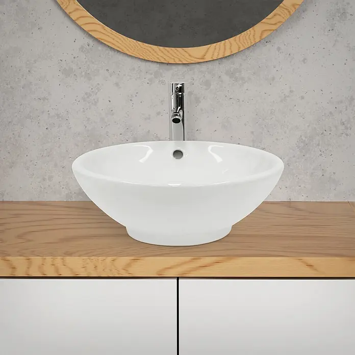 LuxeBath Waschbecken Keramik Waschtisch Ø 420 x 170 mm Rund Weiß -  - Weißes Keramik-Aufsatzwaschbecken mit Chromarmatur auf heller Holzplatte, vor Betonwand und rundem Holzspiegel.