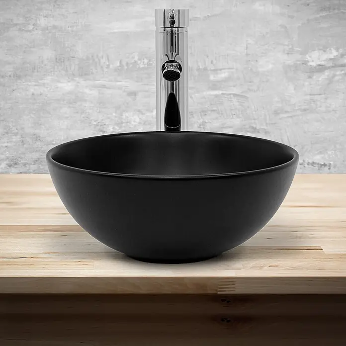 LuxeBath Waschbecken Keramik Schwarz Ø32x13,5cm Rund mit Ablaufgarnitur -  - Schwarzes mattes rundes Aufsatzwaschbecken und hoher Chrom-Mischhahn auf heller Holzplatte.