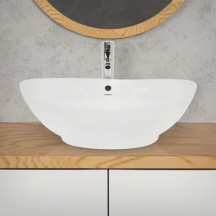 LuxeBath Waschbecken Keramik Waschtisch 590x390x200 mm Weiß Oval Spülbecken -  - Weißes Keramik-Aufsatzwaschbecken mit Chromarmatur auf einer hellen Holzplatte unter einem runden Spiegel.
