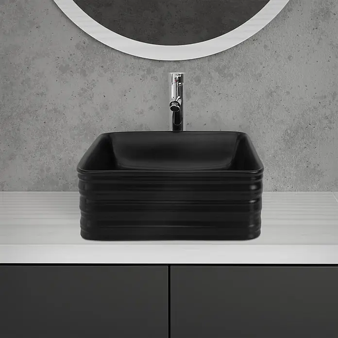 LuxeBath Aufsatzwaschbecken Waschtisch aus Keramik für Badezimmer / Gäste-WC - Ohne Spezialglasur, Schwarz - Schwarzes rechteckiges Aufsatzwaschbecken mit gerippten Seiten und Chromarmatur auf einer hellen Arbeitsplatte mit Spiegel.