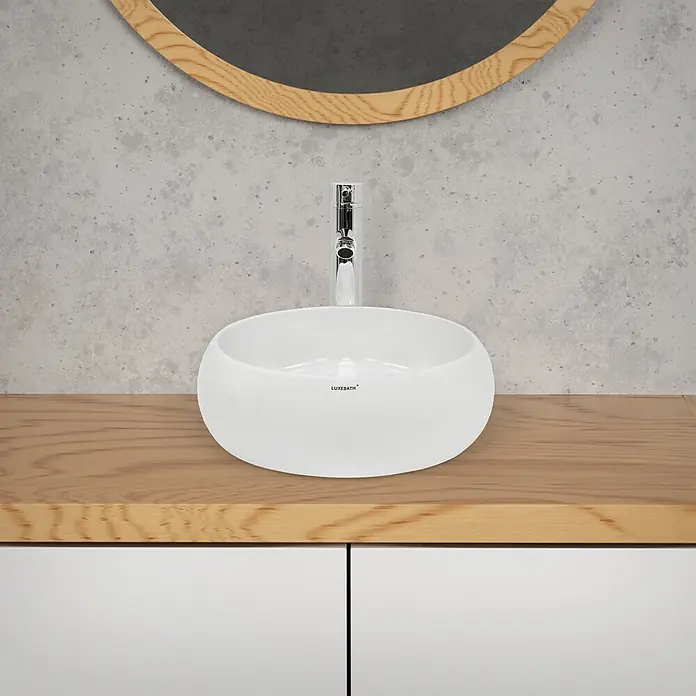 LuxeBath Waschbecken Keramik Waschtisch Ø 350x120 mm Rund Weiß Spülbecken -  - Weißes Keramik-Aufsetzwaschbecken mit Chromarmatur auf heller Holzplatte, unter rundem Holzspiegelrahmen, vor grauer Wand.