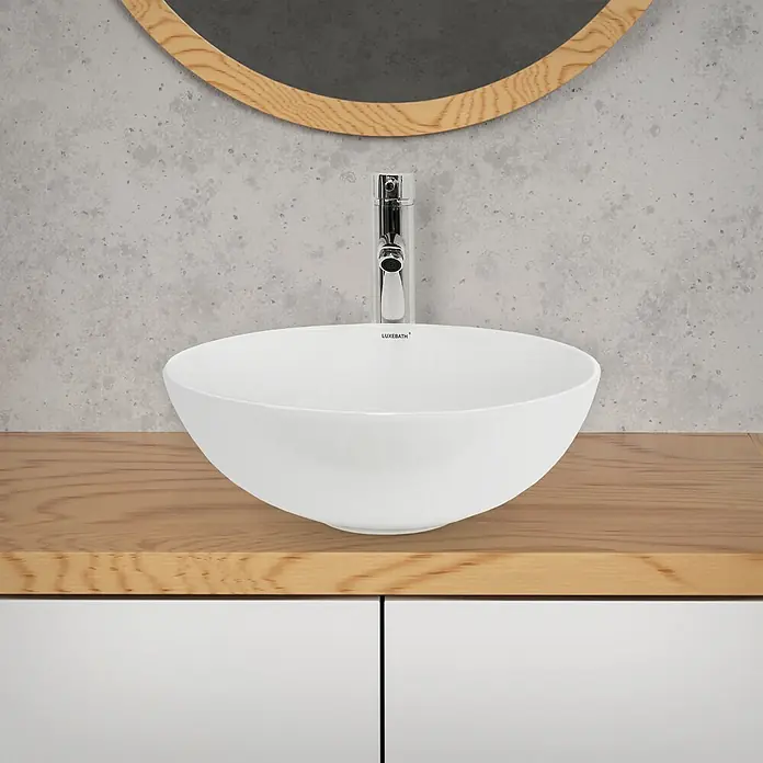 LuxeBath Waschbecken Keramik Waschtisch Ø 400 x 147 mm Rund Weiß Spülbecken -  - Weißes LUXEBATH Keramik-Aufsatzwaschbecken mit Chromarmatur auf einer Holzplatte vor einer Betonwand mit Rundspiegel.
