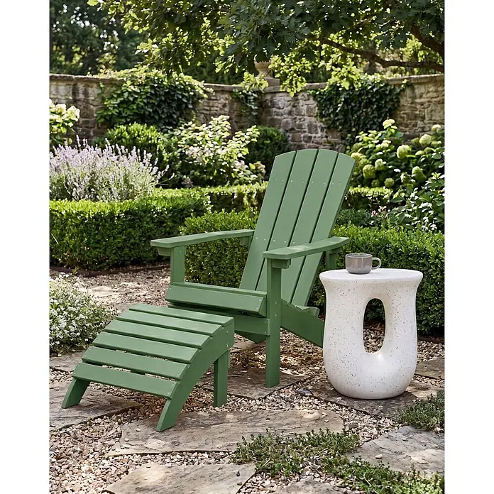 2-tlg Gartenstuhl ADIRONDACK in Grün -  - Grüner Adirondack-Stuhl mit passendem Hocker und weißem Beistelltisch mit Tasse, in einem ruhigen Garten.