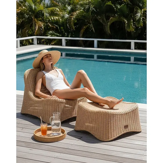 2-tlg Gartenstuhl AIGANI in Naturfarben/Beige -  - Frau entspannt auf einem Rattan-Liegestuhl mit Hocker am Pool in der Sonne.