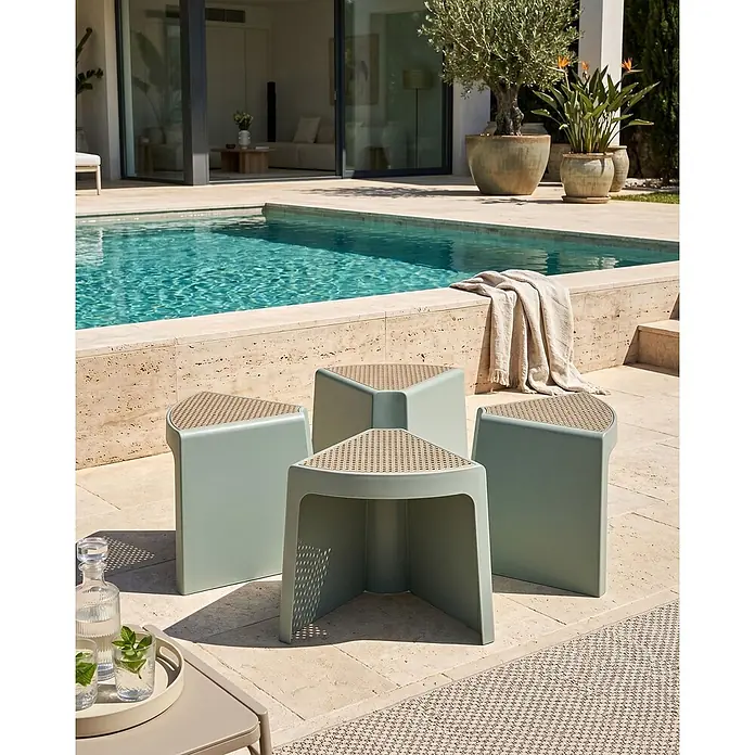4er-Set Gartenstuhl EVROS in Grün/Braun -  - Vier hellgrüne moduläre Hocker mit geflochtenen Oberflächen auf einer Steinterrasse am Pool.