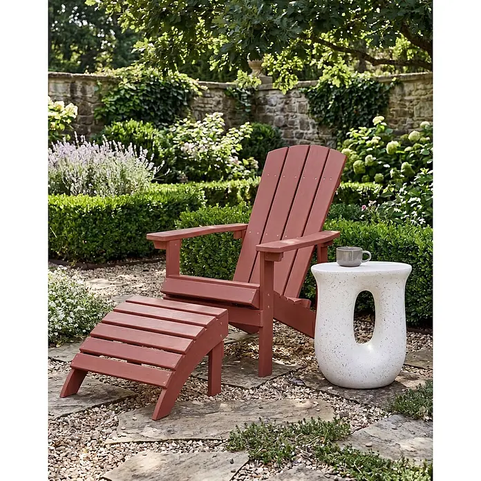 2-tlg Gartenstuhl ADIRONDACK in Rot -  - Roter Adirondack-Stuhl mit passendem Hocker und weißem, gesprenkelten Beistelltisch mit Tasse auf einer Gartenterrasse.