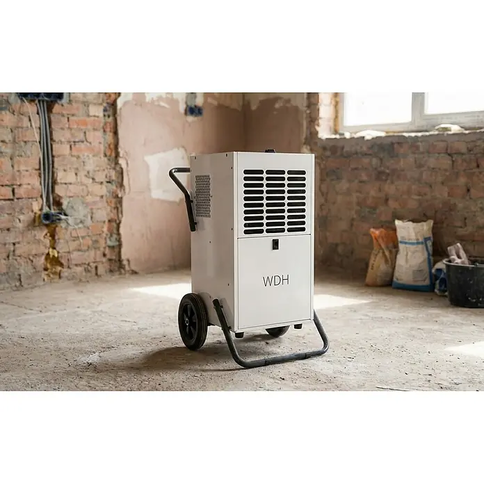 WDH Elektro-Luftentfeuchter Bautrockner WDH-80B - für 180m² - 95 Liter/Tag - ideal für den Dauerbetrieb - Entfeuchtungsleistung: 95 l/Tag, Grau - Weißer industrieller Entfeuchter mit Rollen und Griff in einem Rohbau.