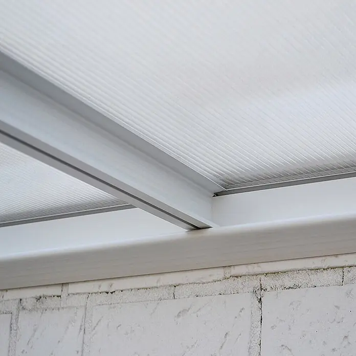 HOME DELUXE - Terrassenüberdachung SOLIS | Farbe: Weiß, Größe: 435 / 442 x 300 / 303 x 278 / 226 cm -  - Transluzente Stegplatten aus Polycarbonat mit weißen Aluminiumprofilen über einer weißen Ziegelwand.