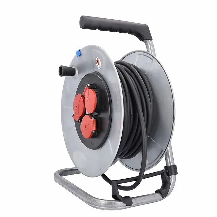 as - Schwabe Metallkabeltrommel 230V 25m H05RR-F 3G1,5 IP44 -  - Graue Kabeltrommel mit schwarzem Kabel, drei roten Steckdosen, schwarzem Griff und Metallständer.