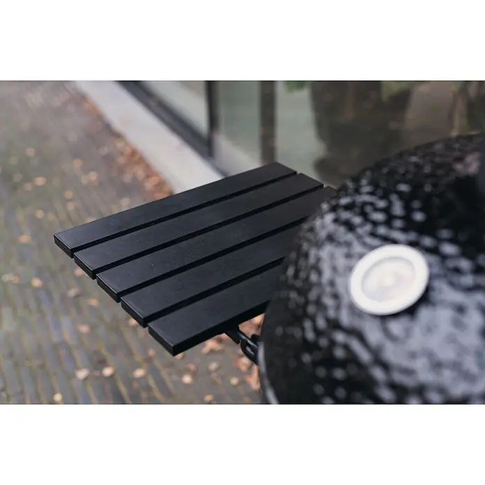 Outr Ahumador Kamado Grill Rock Large - Diámetro de la superficie de la parrilla: 46,8 cm, Negro - Estante lateral de lamas negro unido a una parrilla negra texturizada, mostrado al aire libre.