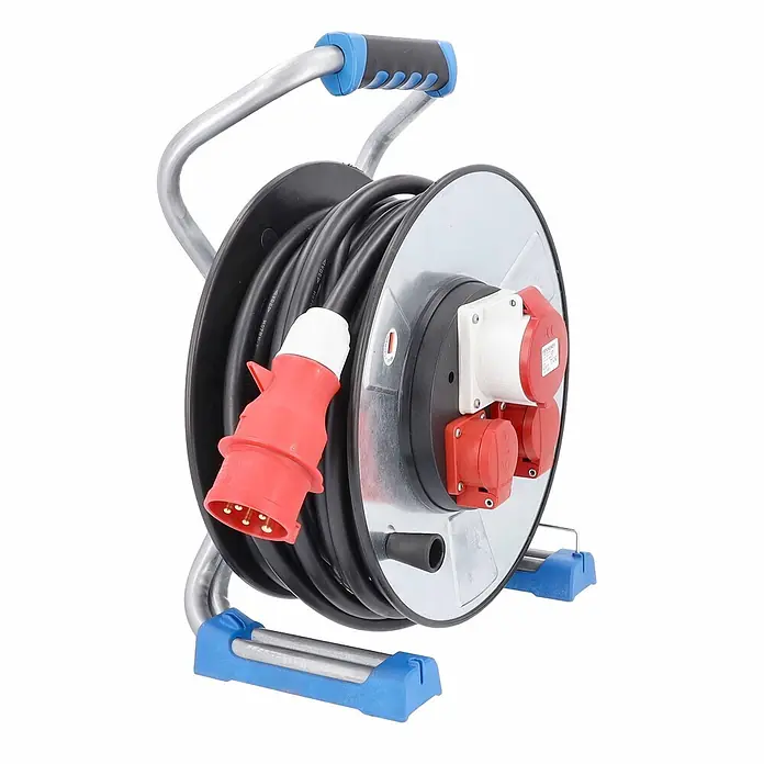 as - Schwabe CEE Metallkabeltrommel Schutzisolierung 400V 25m H07RN-F 5G2,5 IP44 -  - Schwarze Kabeltrommel mit silbernem Rahmen, blauem Griff und roten/weißen Industriesteckdosen für Baustellen.