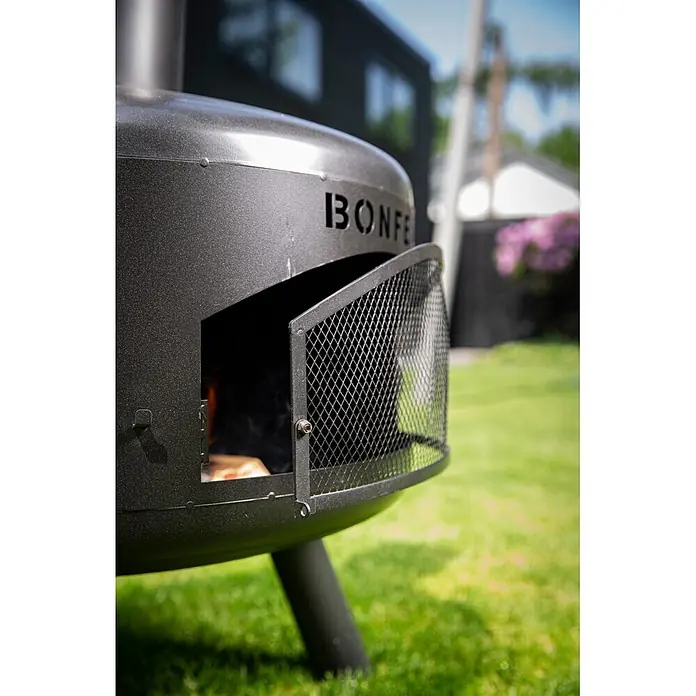 Bonfeu Chimenea de exterior Bongiro - Ø x Al: 55 x 132 cm, Acero, Negro - Fogón exterior BONFE gris oscuro con puerta de malla abierta, mostrando leña lista para el fuego en un jardín.