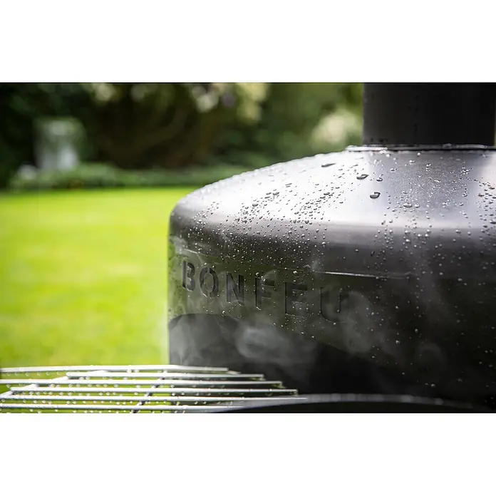 Bonfeu Chimenea de exterior Bongiro - Ø x Al: 55 x 132 cm, Acero, Negro - Parrilla exterior metálica oscura con gotas de agua, muestra el logo 'BONFEU' y humo ligero.