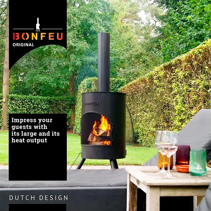 Bonfeu Chimenea de exterior Bonton - Ø x Al: 50 x 172 cm, Acero, Negro - Chimenea exterior de metal negro (Bonfeu) con fuego encendido, que ofrece calidez y ambiente en un jardín junto a muebles de exterior.