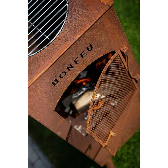 Bonfeu Chimenea de exterior Boncarre - L x An x Al: 35 x 35 x 164 cm, Acero Corten, Marrón óxido - Fogonero exterior de metal oxidado con parrilla y puerta abierta mostrando fuego brillante, "BONFEU" recortado.