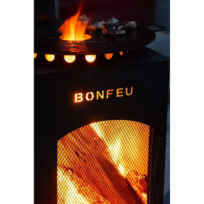 Bonfeu Chimenea de exterior Boncarre - L x An x Al: 35 x 35 x 164 cm, Acero Corten, Marrón óxido - Brasero exterior negro BONFEU con fuego encendido y comida cocinándose en la parrilla.