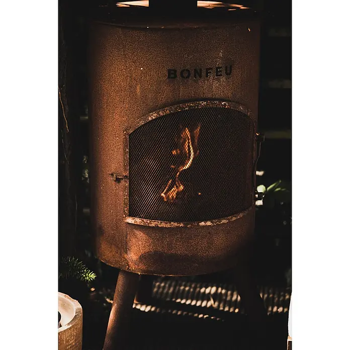 Bonfeu Chimenea de exterior Bonton - Ø x Al: 40 x 145 cm, Acero Corten, Marrón óxido - Chimenea exterior Bonfeu de metal oxidado naranja oscuro con puerta de malla y llamas visibles.
