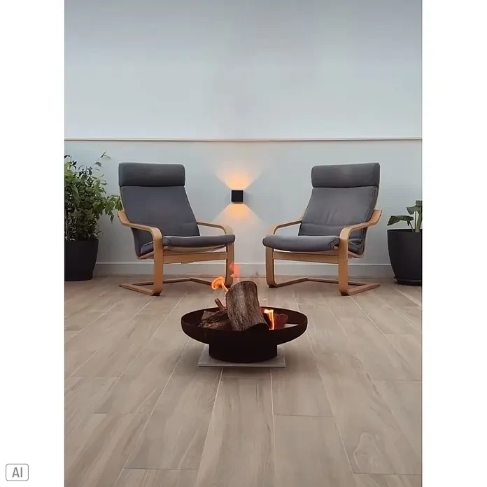 Outr Brasero Jesco - Diámetro: 55 cm, Acero Corten - Brasero de metal oscuro con leña ardiendo, ubicado en una acogedora zona de estar con sillas.
