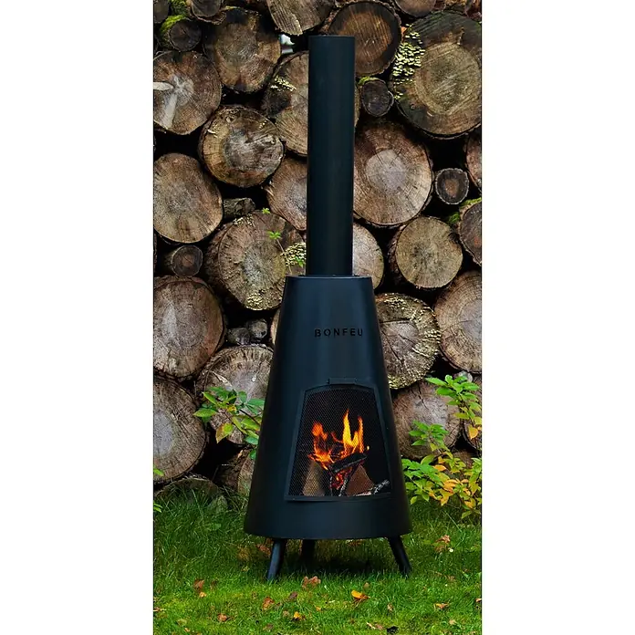Bonfeu Chimenea de exterior Bonpyra - Ø x Al: 50 x 166 cm, Acero, Negro - Chimenea de exterior Bonfeu de metal negro con fuego encendido, sobre césped frente a troncos apilados.