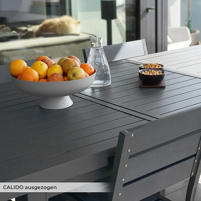 Home Deluxe Gartentisch CALIDO -  - Grauer, ausgezogener CALIDO Esstisch mit Stühlen, Obst und Snacks für den Außenbereich.
