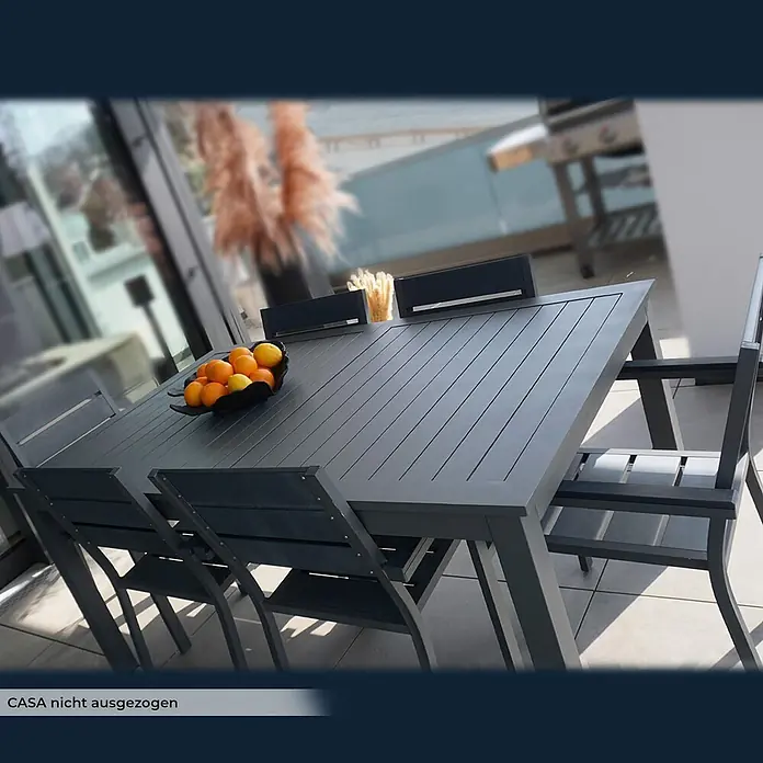 Home Deluxe Gartentisch CASA -  - Dunkelgraues Aluminium-Gartenset mit Tisch und Stühlen auf einer Terrasse, darauf eine Schale mit Orangen und Zitronen.