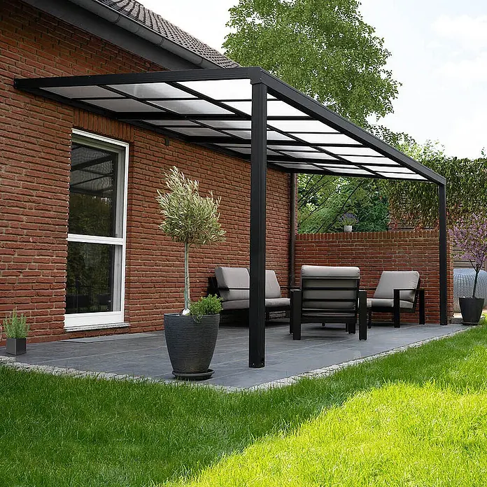 Home Deluxe Terrassenüberdachung SOLIS DELUXE Grau 290 x 295 x 233 / 272 cm -  - Schwarze Aluminium-Pergola mit transparenten Dachplatten, die einen schattigen Terrassenbereich neben einem Backsteinhaus schafft.