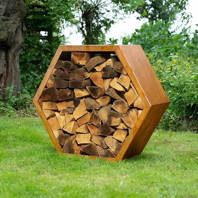 Home Deluxe Holzlege ANTARES Menge: 3 -  - Rostfarbenes hexagonales Metall-Brennholzregal, gefüllt mit gestapelten Holzscheiten.