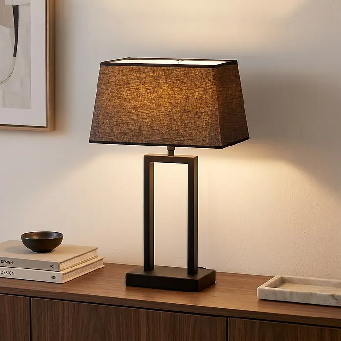 Home Sweet Home Lampenschirm Largo - L x B x H: 19 x 35 x 19 cm, Night Black, Stoff, Eckig - Schwarze Tischlampe mit rechteckigem Stoffschirm und geometrischem Metallsockel, beleuchtet auf einem Holzschrank.
