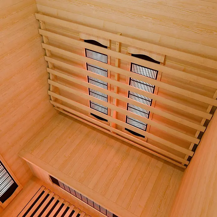 Infrarotkabine/Wärmekabine Nyborg S120V mit Vollspektrum-, Flächenstrahler & Hemlockholz -  - Saunainnenraum aus hellem Holz mit Lamellenwänden und Bänken, mit leuchtenden Infrarotheizungen hinter Schutzgittern.