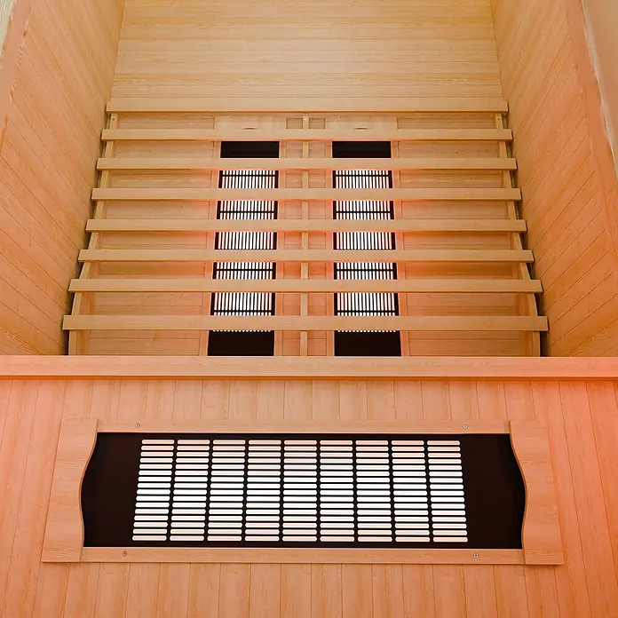 Infrarotkabine/Wärmekabine Nyborg S120V mit Vollspektrum-, Flächenstrahler & Hemlockholz -  - Innenraum einer hellen Infrarotsauna aus Holz mit mehreren rot glühenden Heizungen und Lattenbänken.