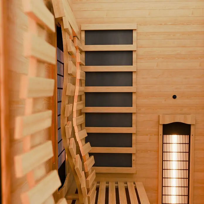 Infrarotkabine Kiruna130 Premium -  - Innenansicht einer hellen Holzsauna mit Lattenwänden, einer Holzbank und glühenden Infrarot-Heizpaneelen.