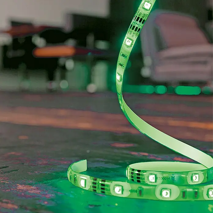 LED-Band - Länge: 3 m, Lichtfarbe: RGB, 16 W - Nahaufnahme eines grünen LED-Streifens, der sich auf einer Oberfläche windet, mit einer verschwommenen Hintergrundszene.