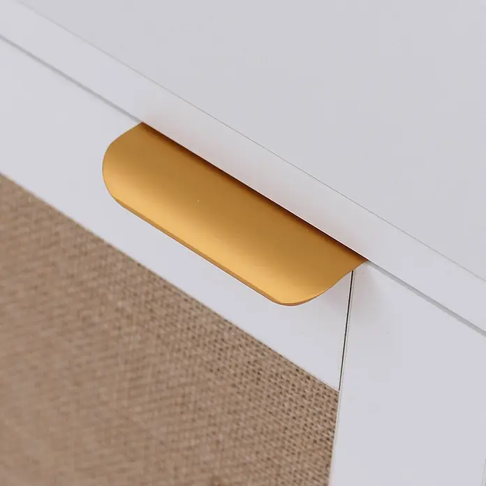 Mendler Kommode HWC-P50 - L x B x H: 80 x 40 x 80 cm, Weiß - Goldener C-förmiger Griff an einem weißen Schrank oder einer Schublade, mit beiger Webstruktur darunter.