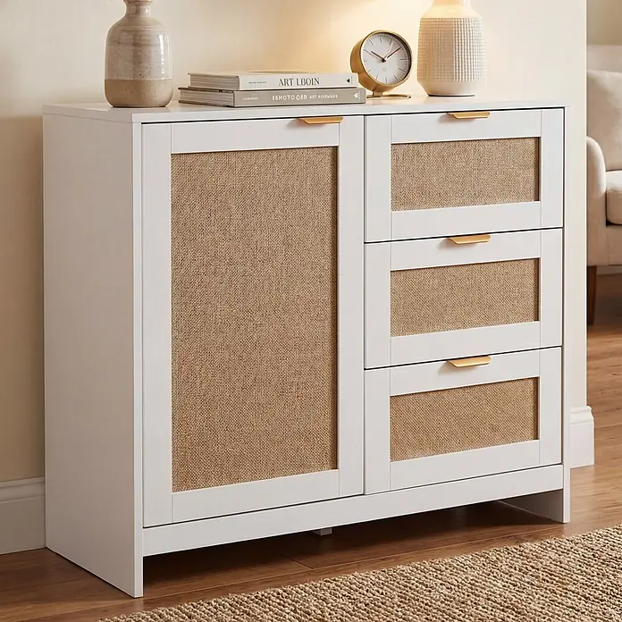 Mendler Kommode HWC-P50 - L x B x H: 80 x 40 x 80 cm, Weiß - Weißer Schrank mit gewebten Paneelen und goldenen Griffen, dekoriert in einem Wohnbereich.