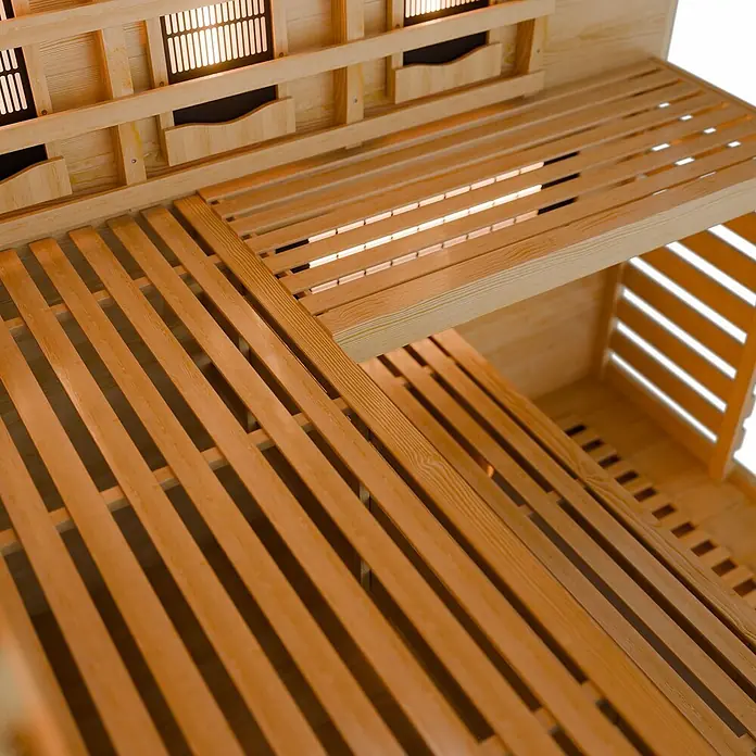 Artsauna Elementsauna - L x B x H: 150 x 150 x 200 cm - Innenansicht einer hellen Holzsauna mit Lattenbänken und glühenden Heizelementen.
